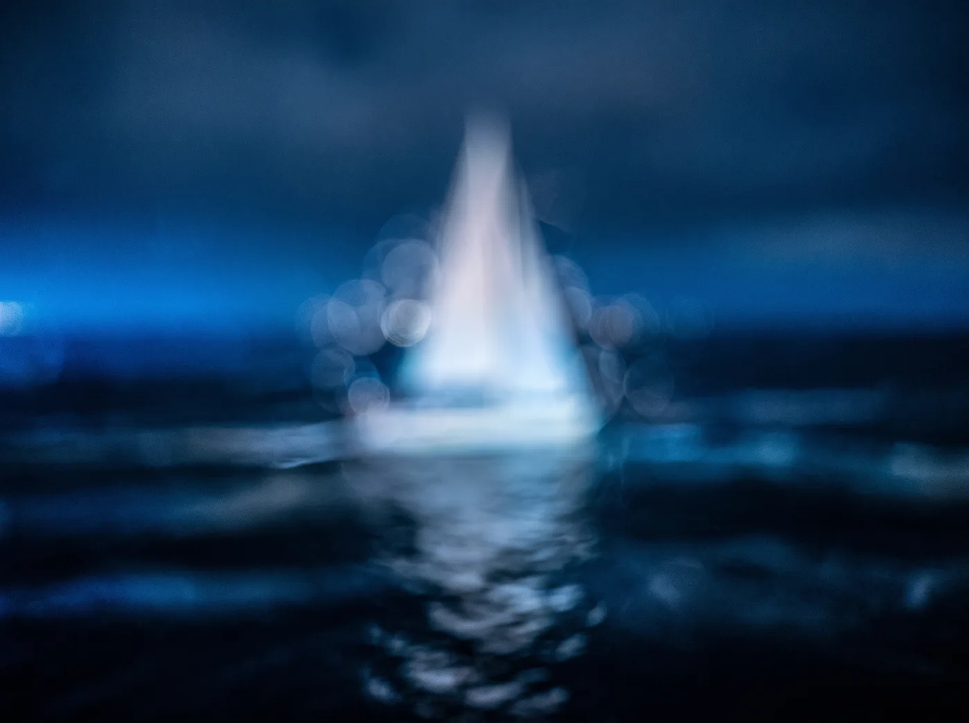 Abstract blurred silhouette of a sail-like device at sea, night